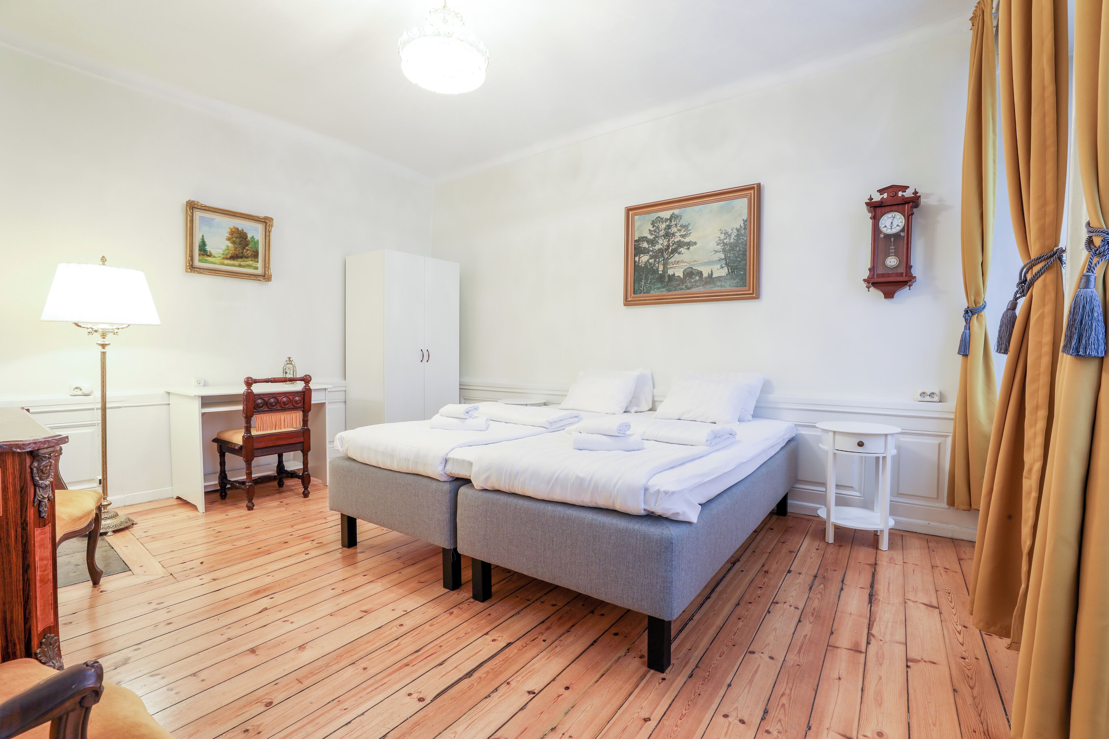 A bedroom with a bed, a desk, a chair, a lamp, and a clock on the wall.