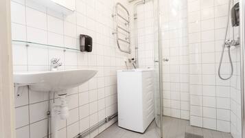 Une salle de bain moderne avec un lavabo blanc, une douche en verre et un lave-linge encastré.