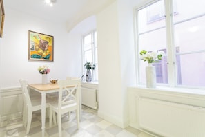 A dining area with a table and chairs, a window with a view, and a painting on the wall. - ApartDirect Gamla Stan II (Stockholm)