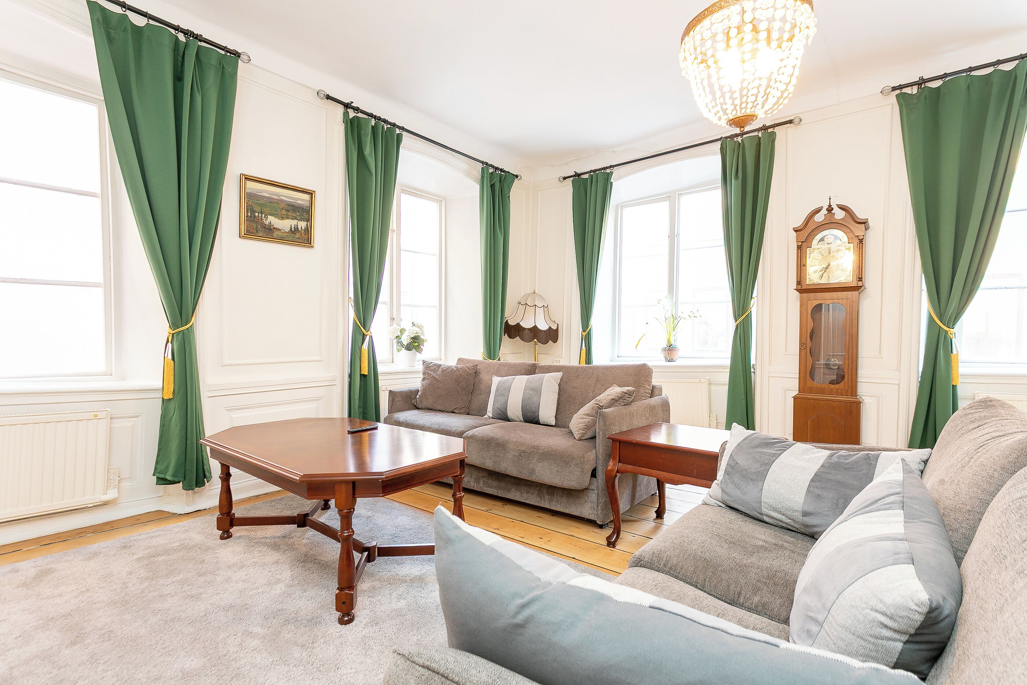 A living room with a sofa, a coffee table, a chandelier, and a clock.