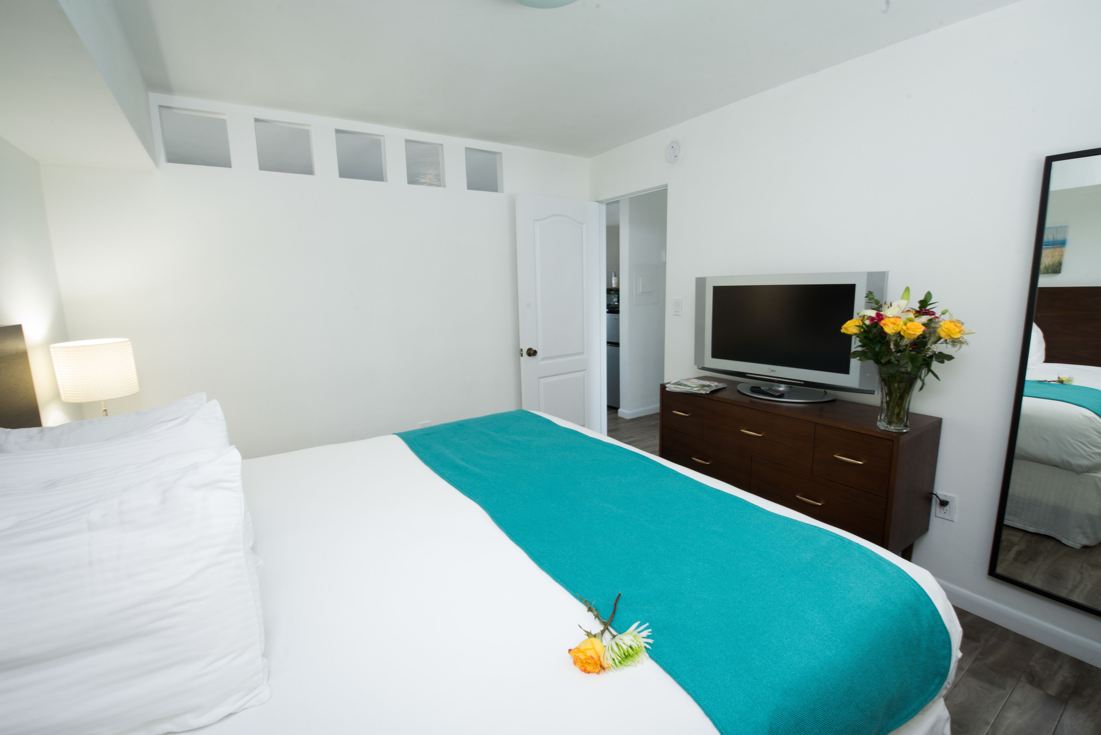 A hotel room with a bed, a TV, a dresser, and a mirror.