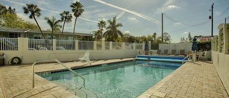 A swimming pool with a tiled deck, palm trees, and a building with a sign reading "SARASO MINI MARINE".