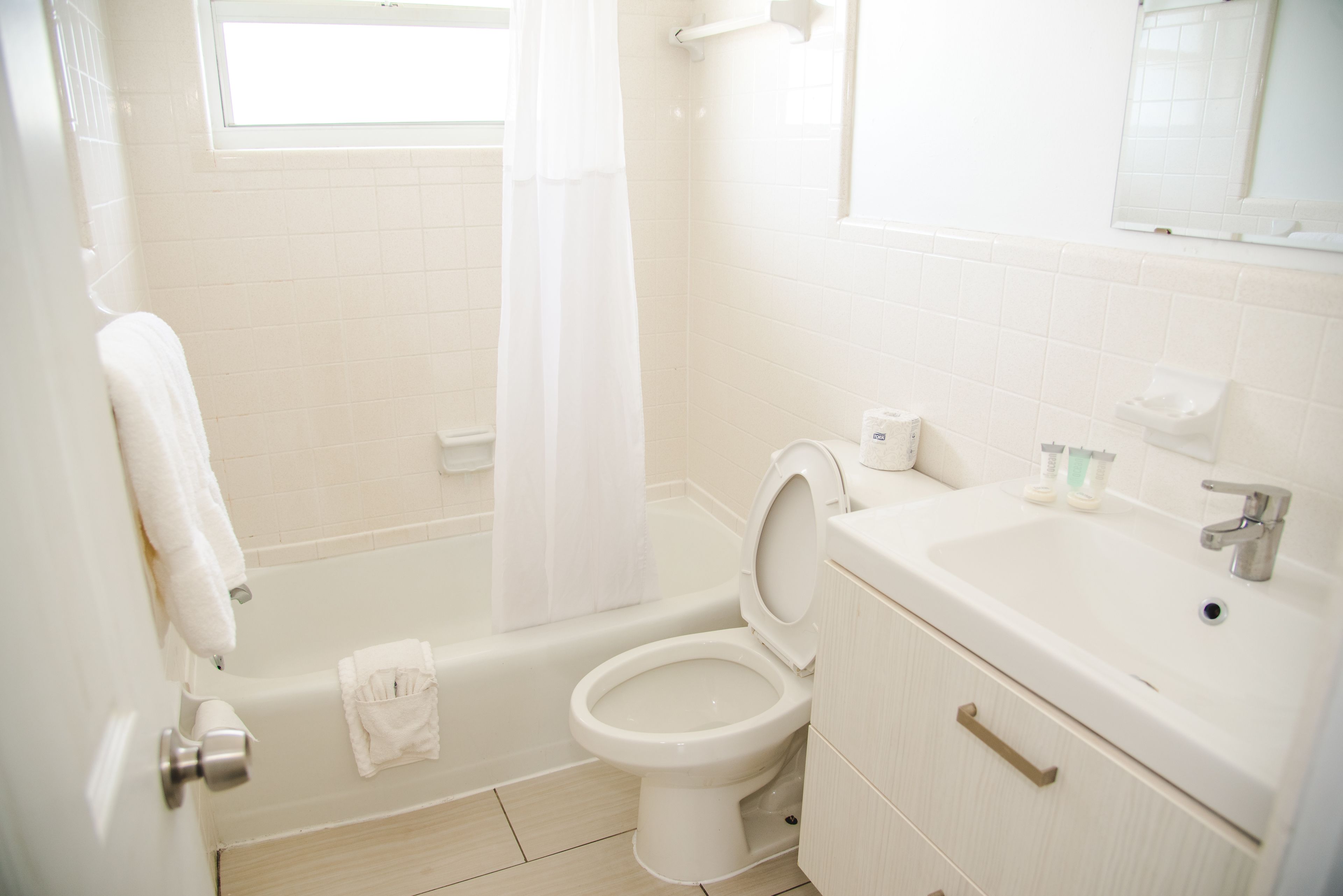 A bathroom with a bathtub, toilet, sink, and a window.