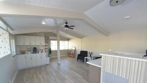 Amplia sala de estar con cocina, comedor y mostrador de recepción.