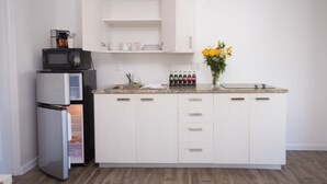 Una cocina moderna con armarios blancos, microondas integrado, refrigerador y una encimera con un florero.