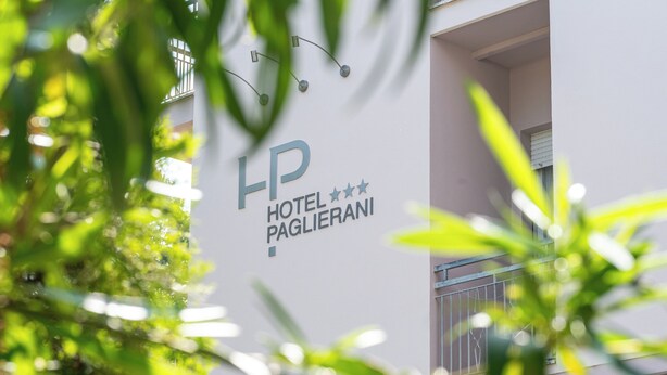 Une enseigne d’hôtel portant le nom « HP HOTEL PAGLIERANI » et un balcon doté d’une balustrade en métal.
