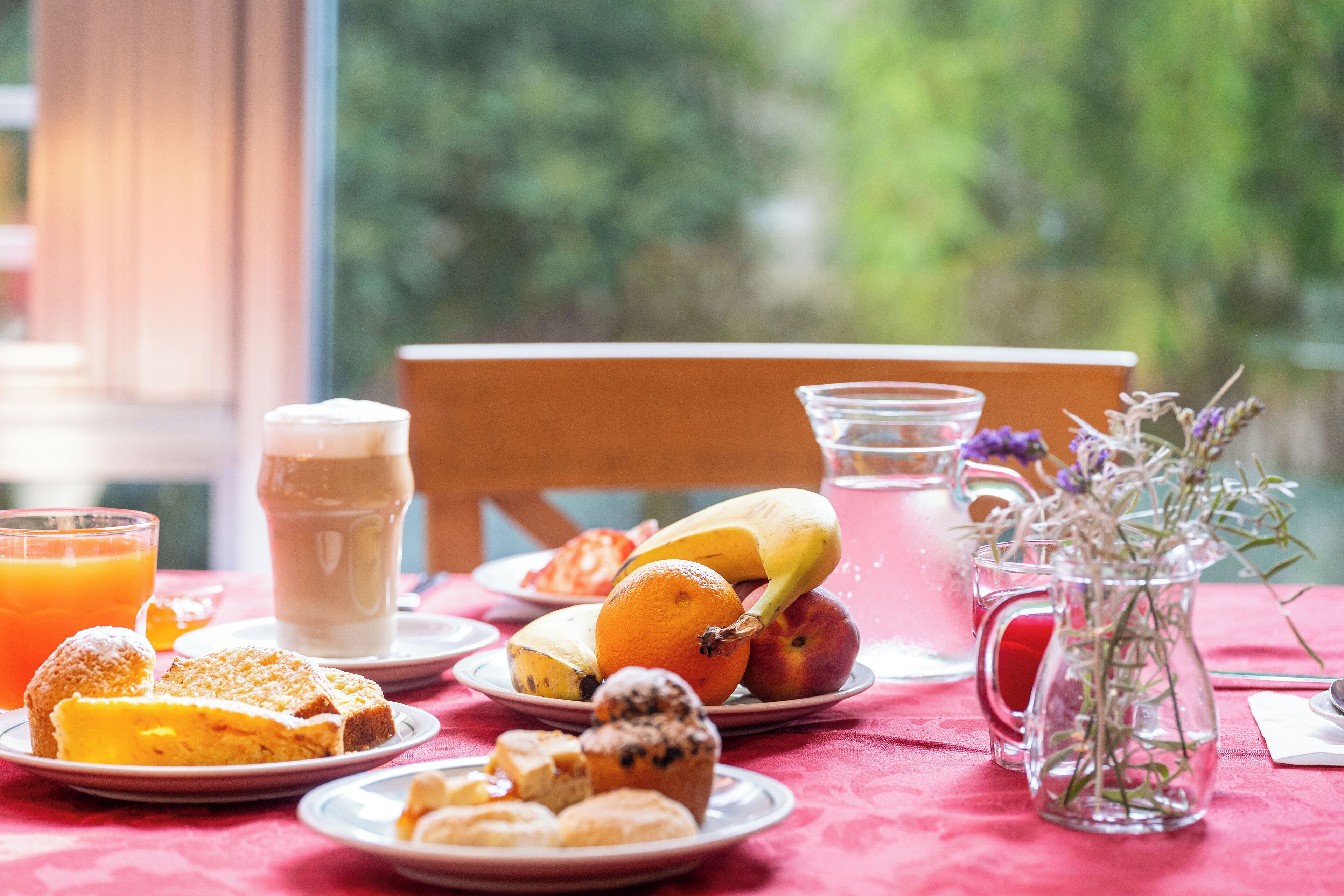 Une table de petit-déjeuner avec des assiettes remplies de nourriture, une carafe et un verre de jus d’orange.