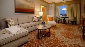 A hotel room with a sofa, armchairs, a coffee table, and a large painting on the wall.