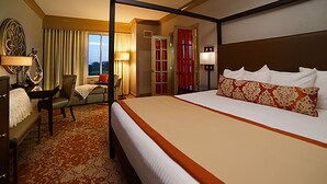 A hotel room with a large bed, a desk, a chair, and a view of the outdoors.