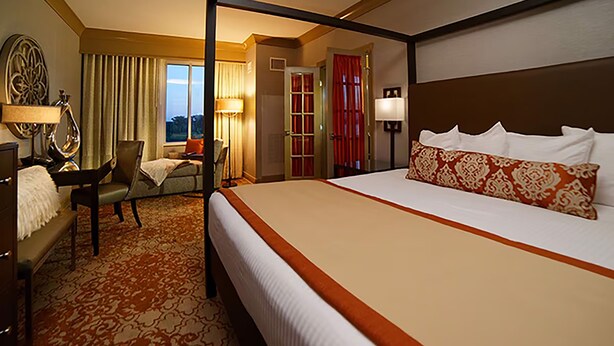 Habitación de hotel con una cama grande, un escritorio, una silla y vistas al exterior.