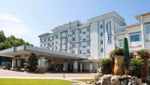 A multi-story hotel with a modern design, featuring a covered entrance and a landscaped area with potted plants.