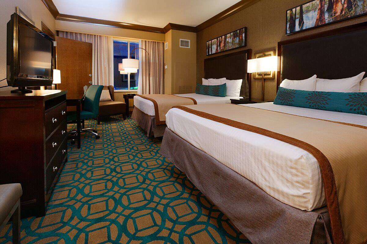 A hotel room with two beds, a TV, a desk, and a chair.