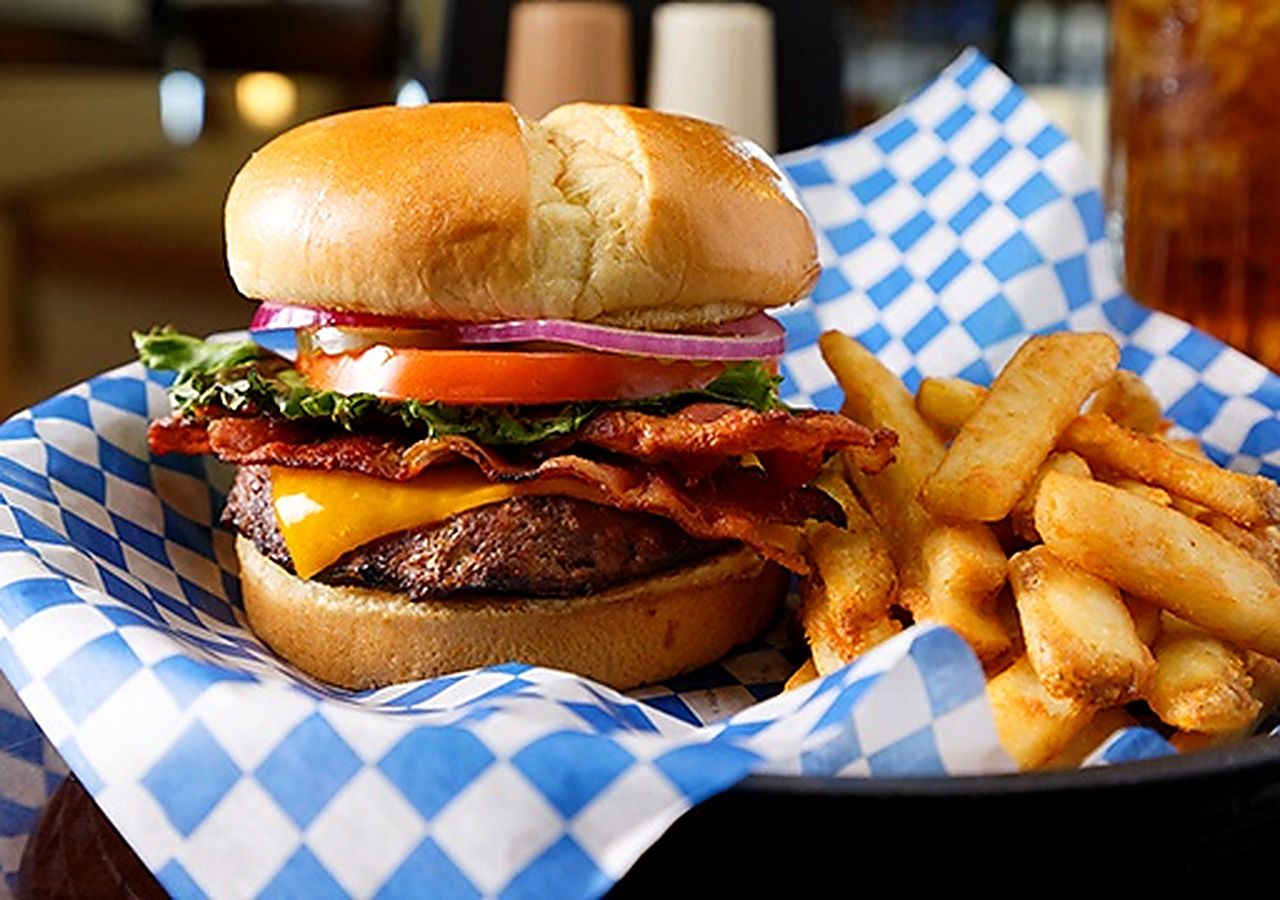 A burger with fries in a paper container.