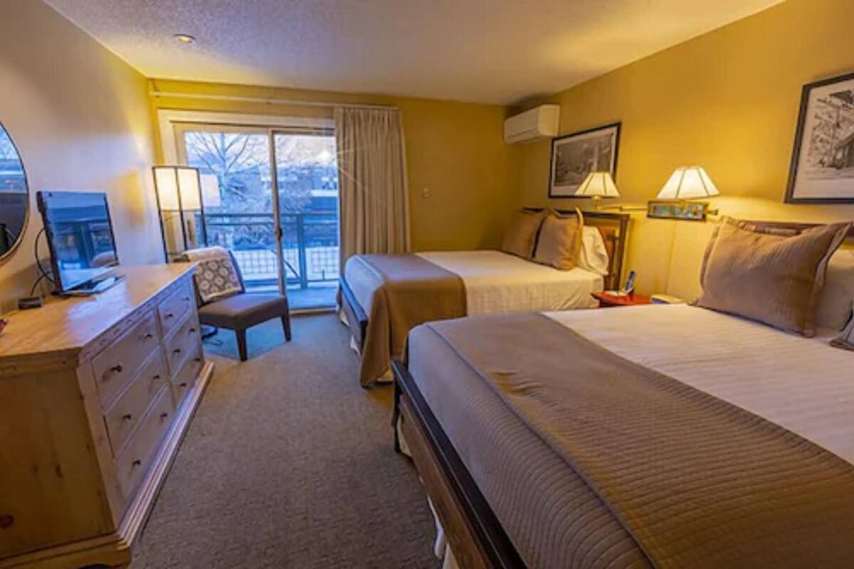 Une chambre d’hôtel avec deux lits, un bureau, une chaise et une commode.