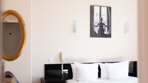 Une chambre d’hôtel avec un lit double, une table de chevet avec une lampe, un miroir et un tableau encadré au mur.