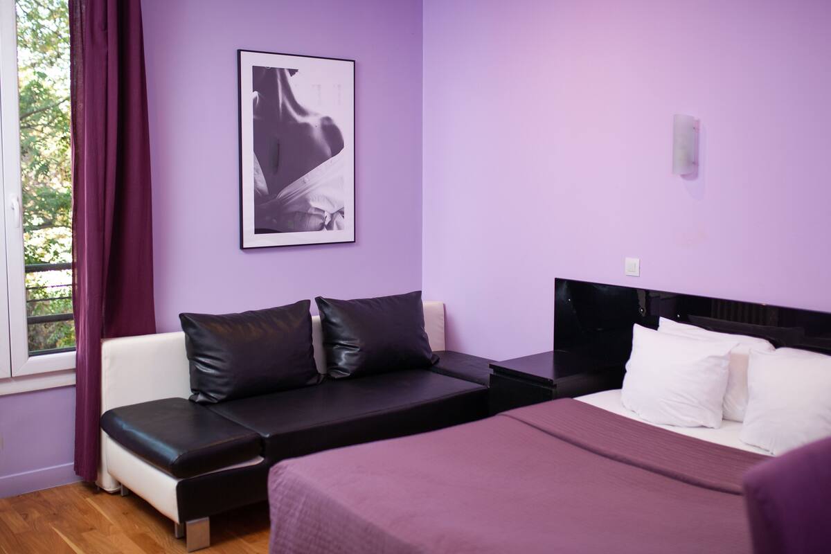 Ein Zimmer mit einem Bett, einem Schlafsofa und einem Vorhangfenster.