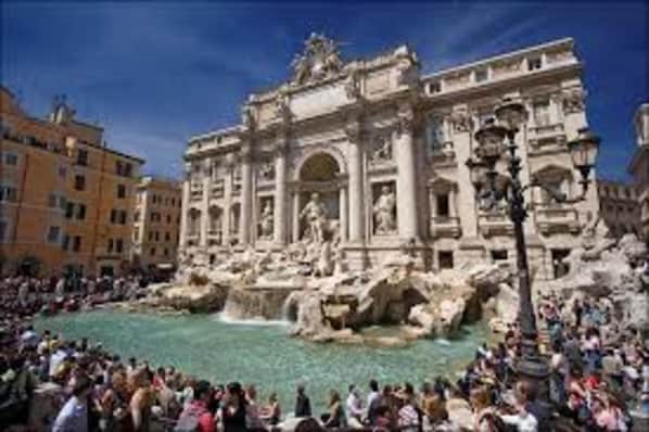 A historic building with classical architecture, a central fountain, and a crowd of people.