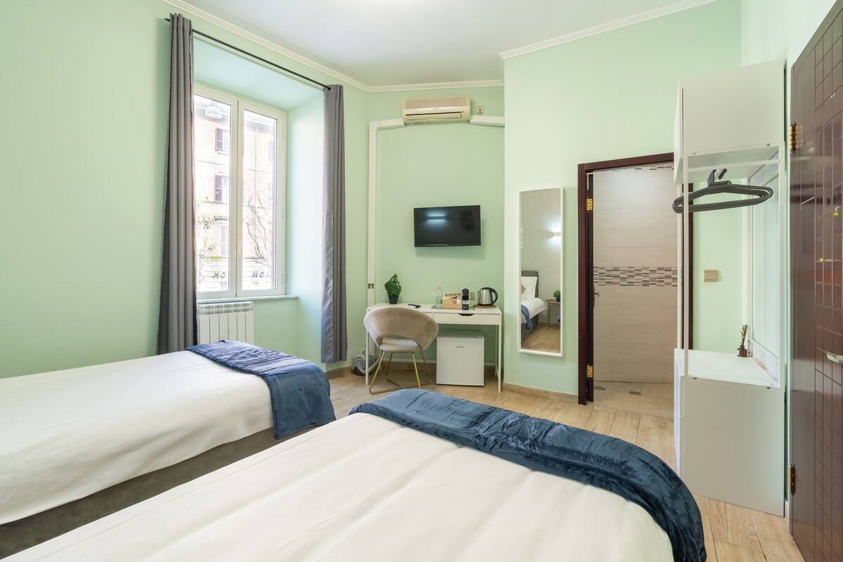 Une chambre d’hôtel avec deux lits, un bureau, une télévision et une armoire.