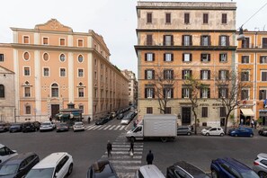 A street view with parked cars, a crosswalk, and buildings with balconies and windows. - Giusi Rooms - Esquilino Harmony Guesthouse (Rome)