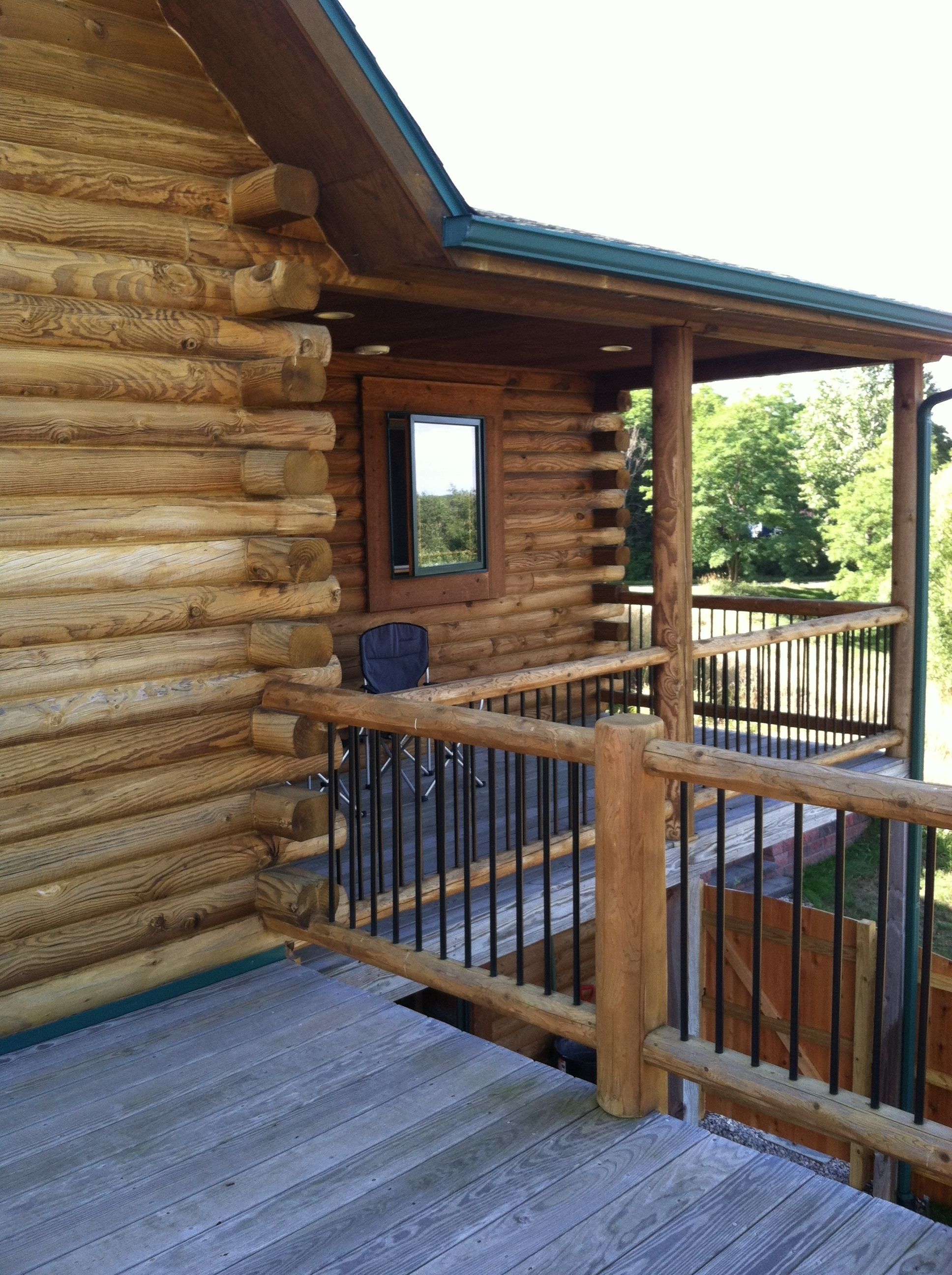 A log cabin with a wooden deck and a small window.