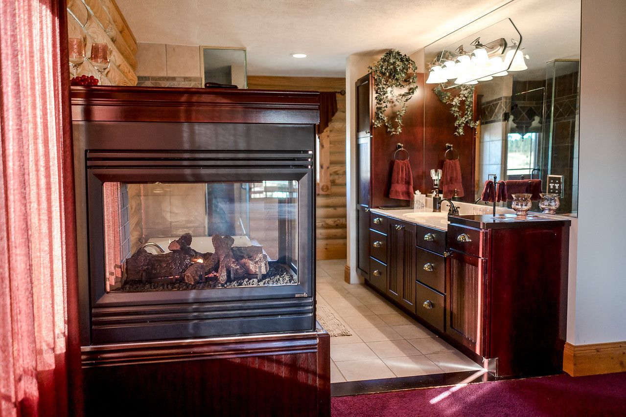 A wooden fireplace with a glass door, a wooden cabinet with drawers, and a mirror above the sink.