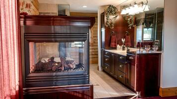 A wooden fireplace with a glass door, a wooden cabinet with drawers, and a mirror above the sink.