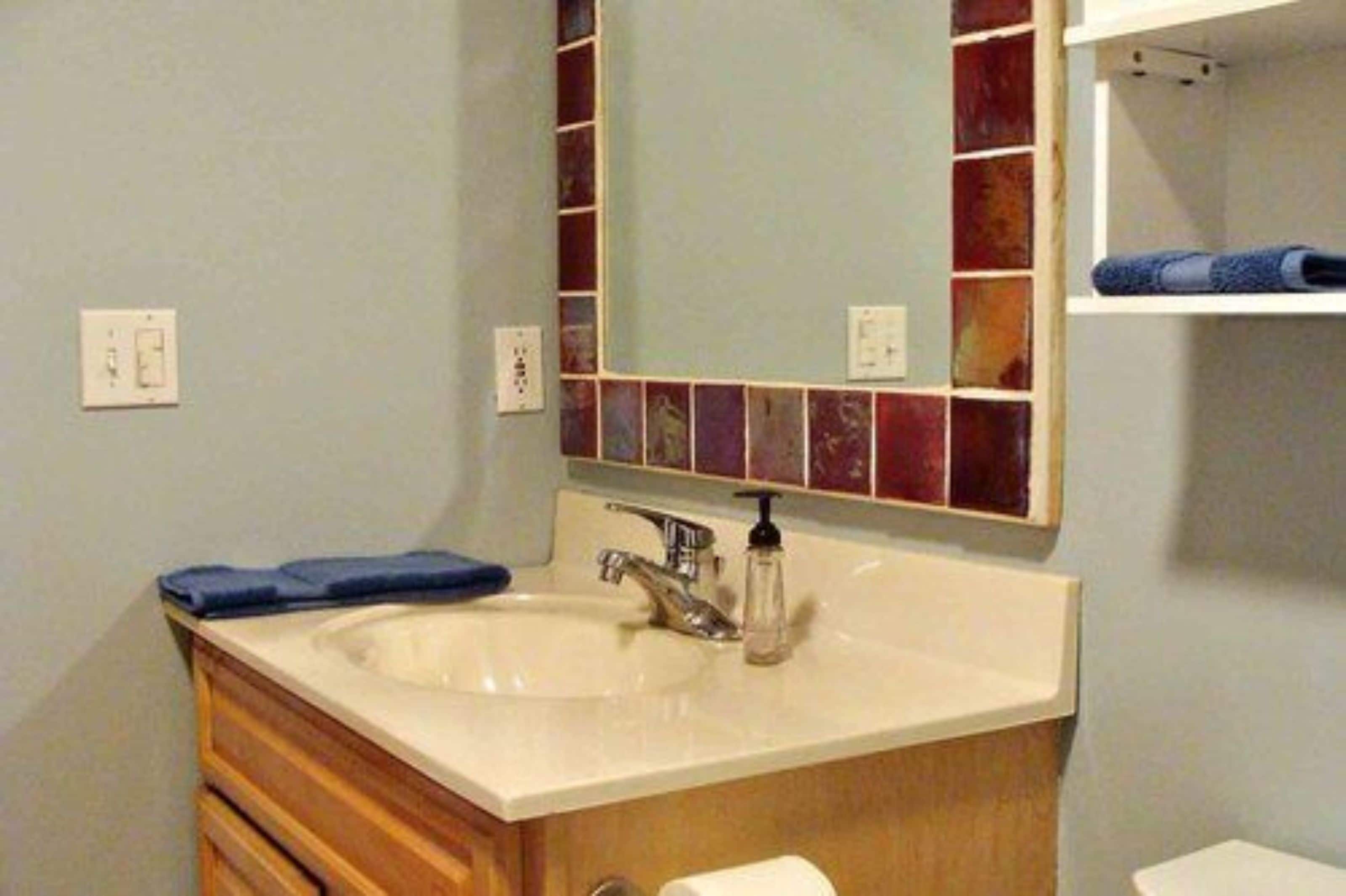 Un baño con lavamanos, espejo y perchero para toallas.