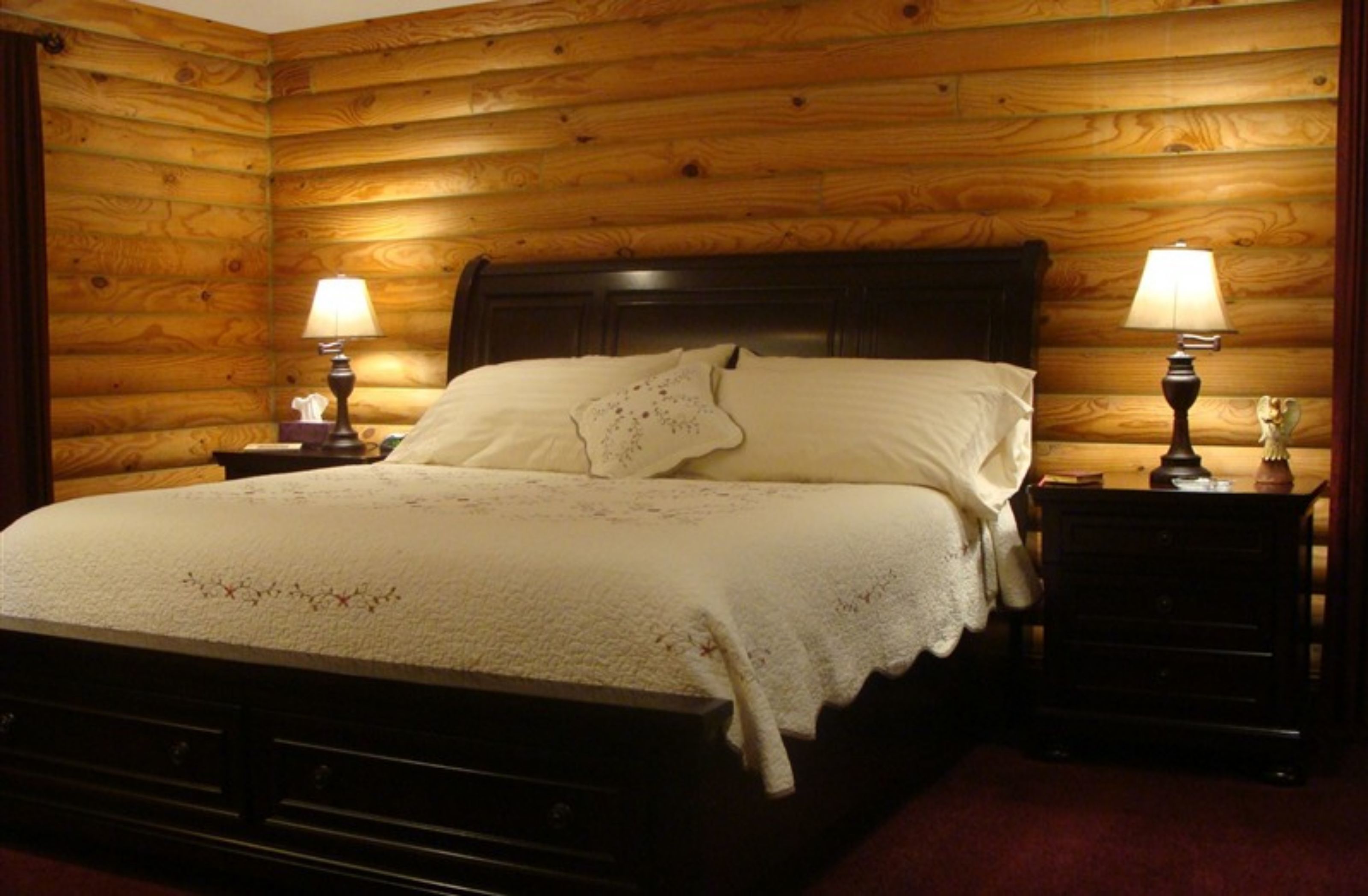 A wooden-paneled room with a bed, two nightstands, and lamps.