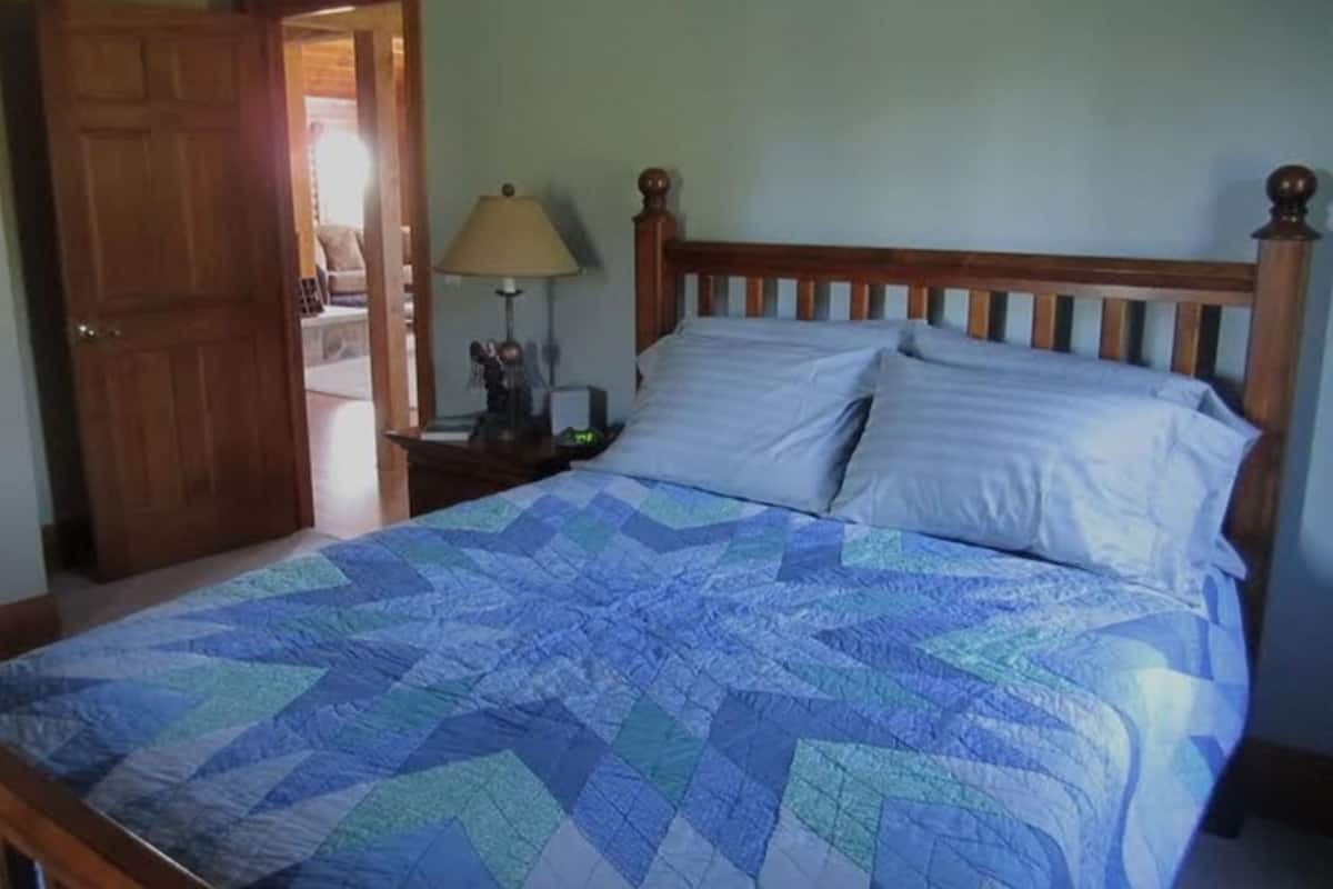 A bedroom with a wooden bed, a nightstand, a lamp, and a door.