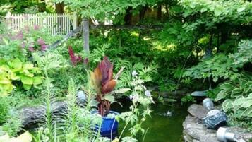 A lush garden with a variety of plants and a small pond.