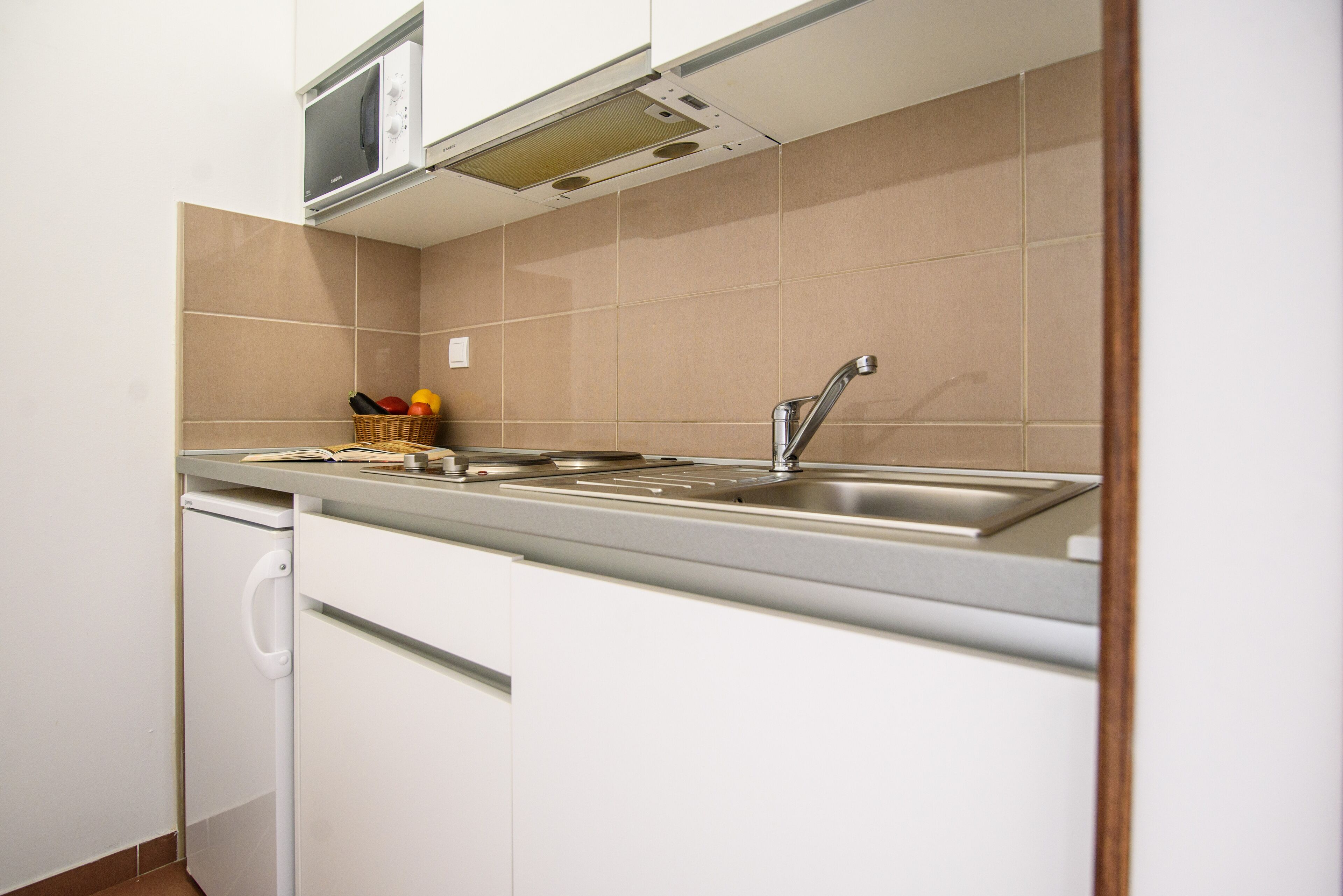 A compact kitchen with a built-in microwave, a stainless steel sink, and a dishwasher.