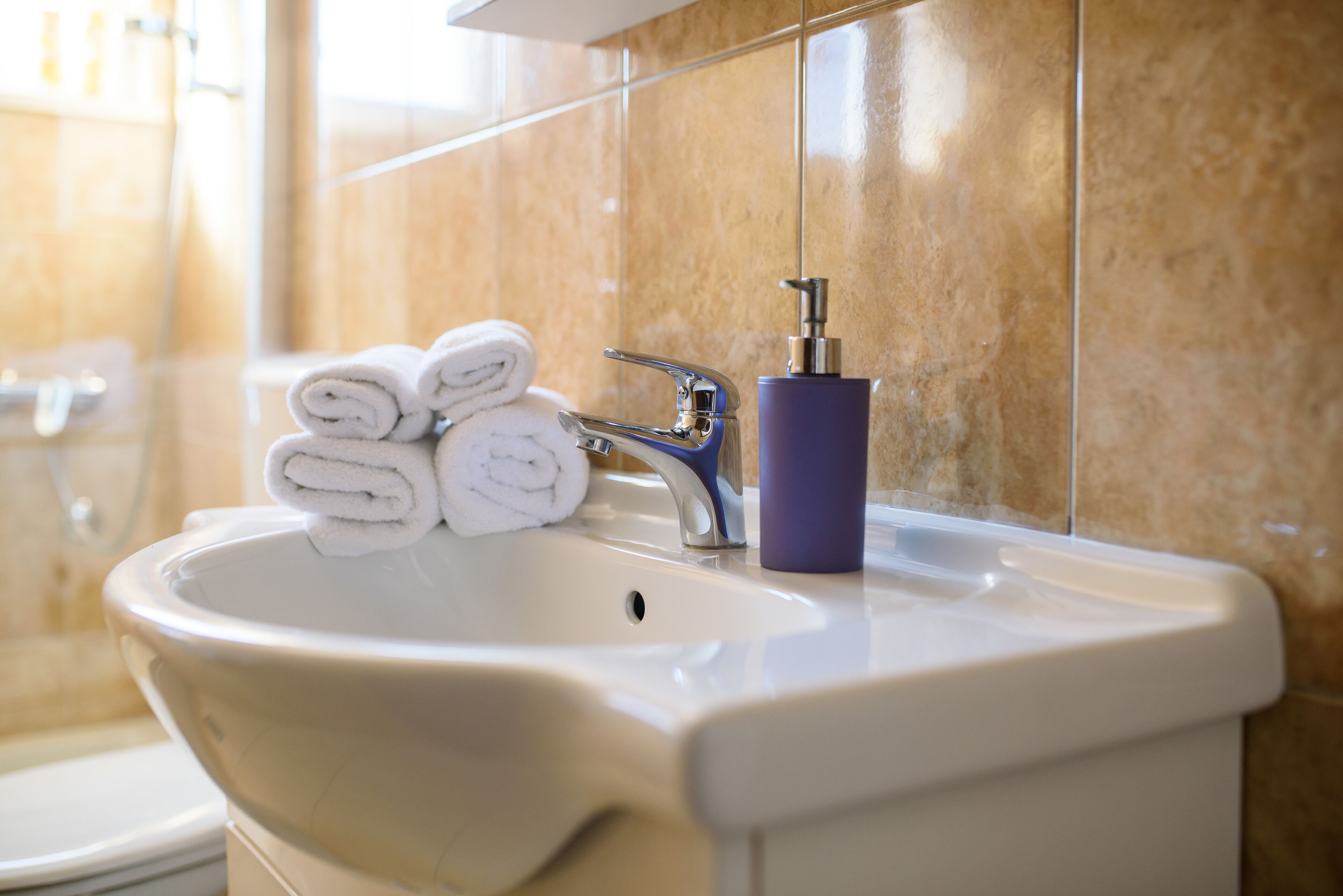 A bathroom sink with a towel dispenser and a toilet.