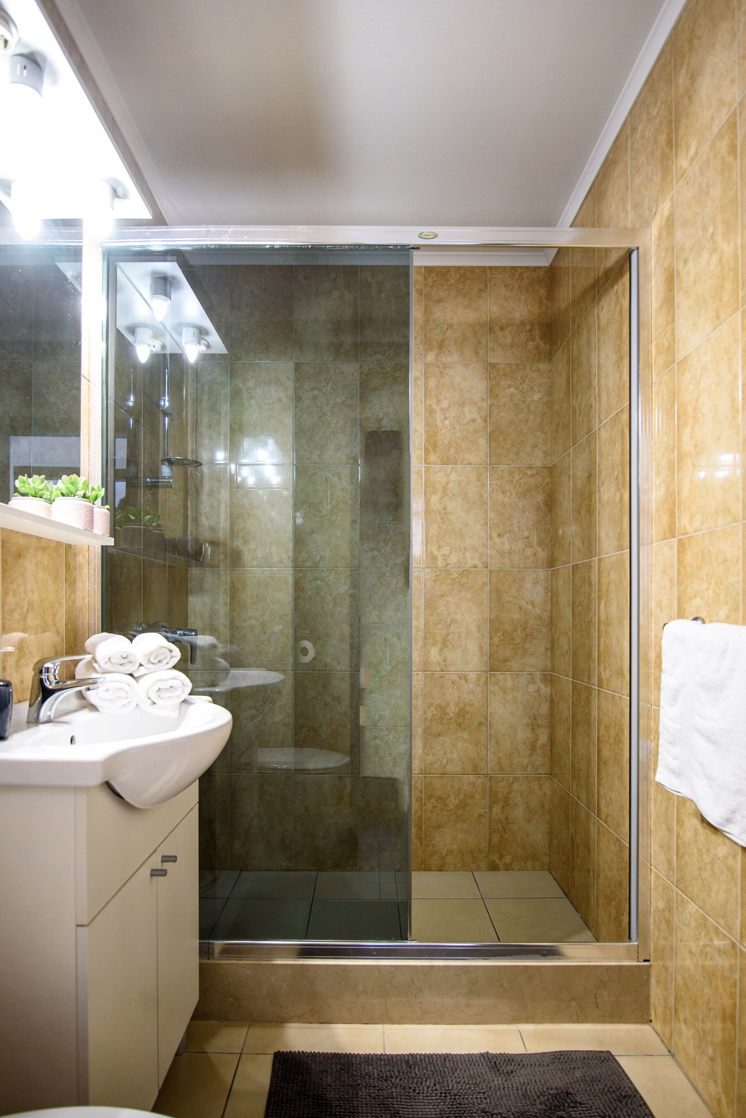 A modern bathroom with a glass-enclosed shower, a white sink, and a mirror above it.