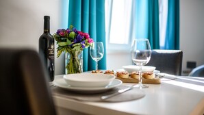 A dining table set with plates, glasses, a bottle, and a floral arrangement.
