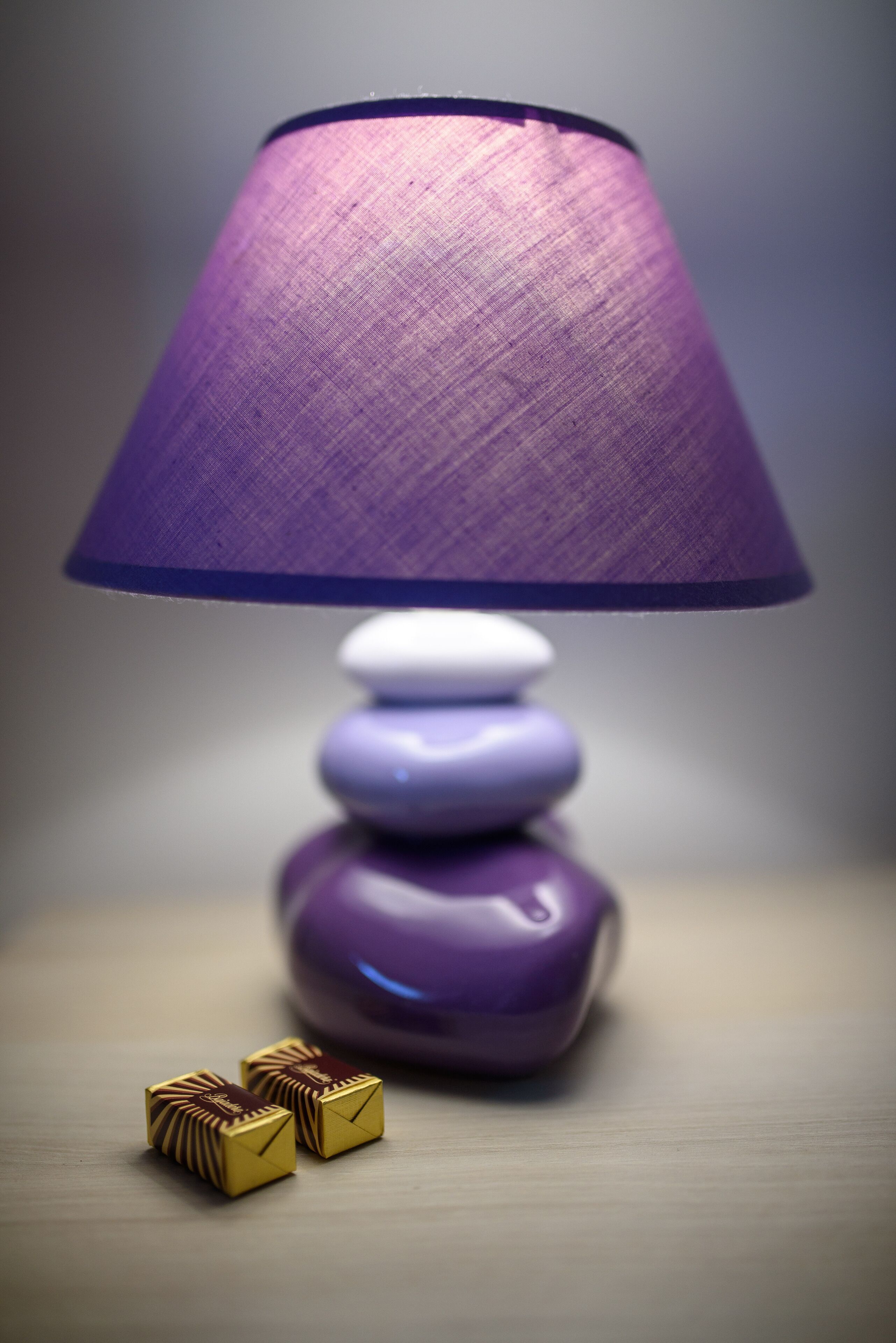 A purple lamp with a textured shade on a wooden surface.