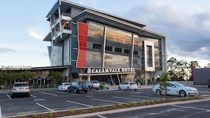 Un hotel moderno con un letrero llamativo, varios espacios de estacionamiento y un cielo despejado.