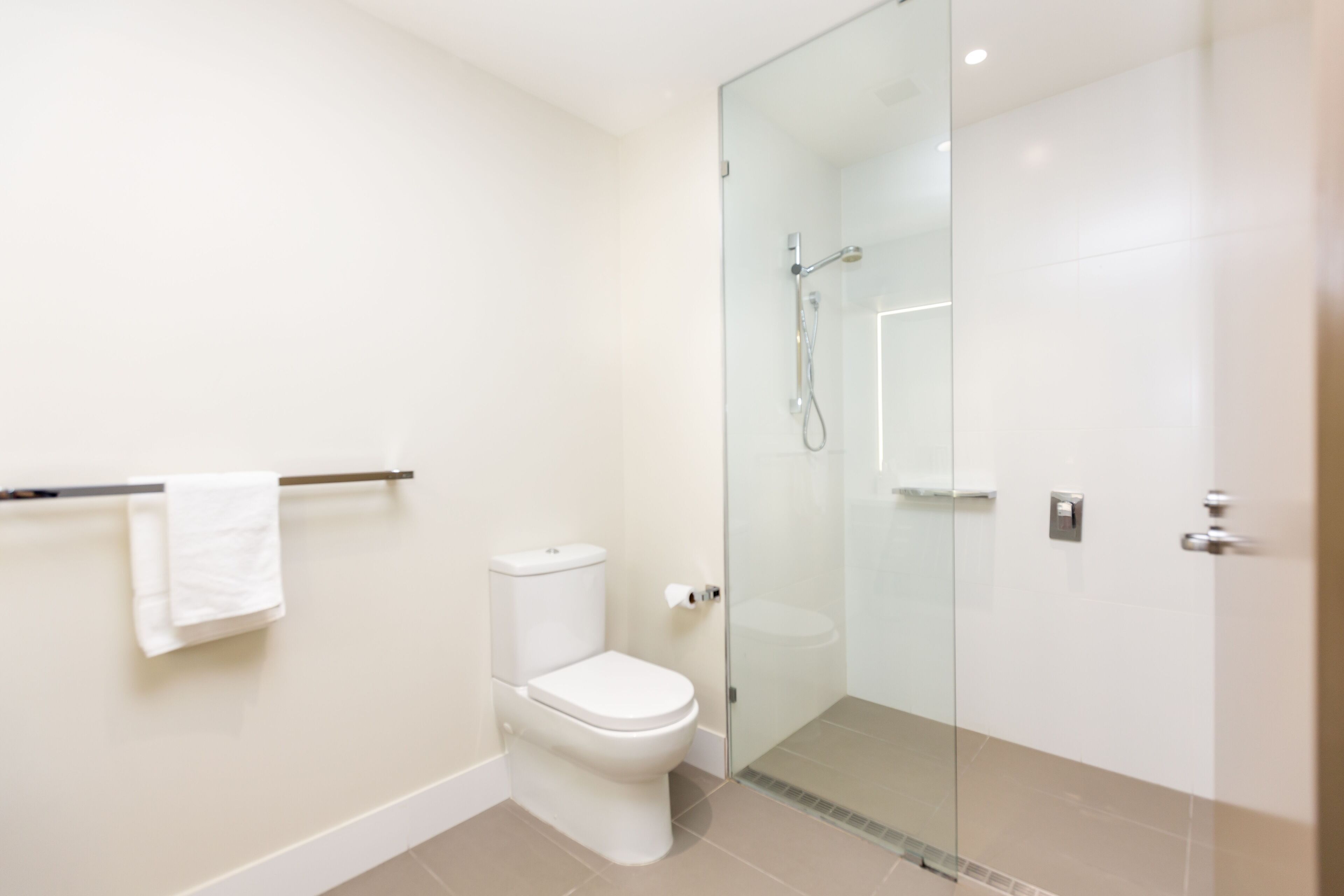 Une salle de bain moderne avec une douche à parois de verre, des toilettes et un porte-serviettes.