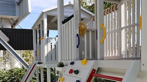 Una estructura de juegos infantiles con escalones para trepar y barras de seguridad de colores.