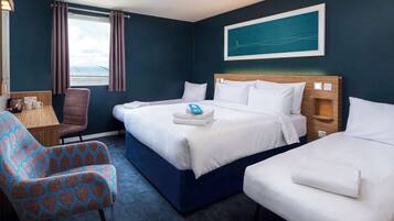 A hotel room with a large bed, two smaller beds, a chair, a desk, and a window with curtains.