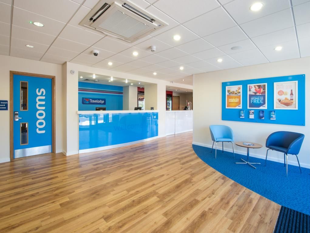 A reception area with a blue counter, two blue chairs, and a sign indicating 'rooms'.