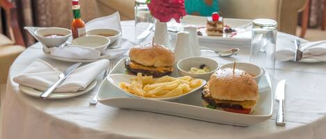A dining table set with a burger, fries, and condiments.