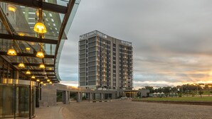 Un edificio moderno con fachada de vidrio y un área de estacionamiento al frente.