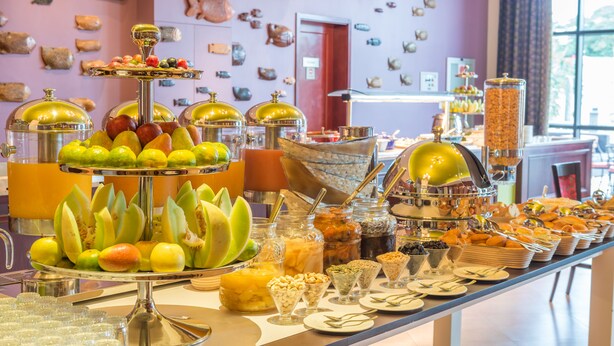 Un bufé con diversas frutas, nueces y aderezos.