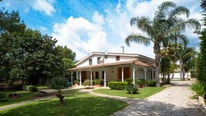 A two-story house with a covered porch, surrounded by a well-maintained lawn and palm trees. - B&B A Casa di Joy (Lecce)