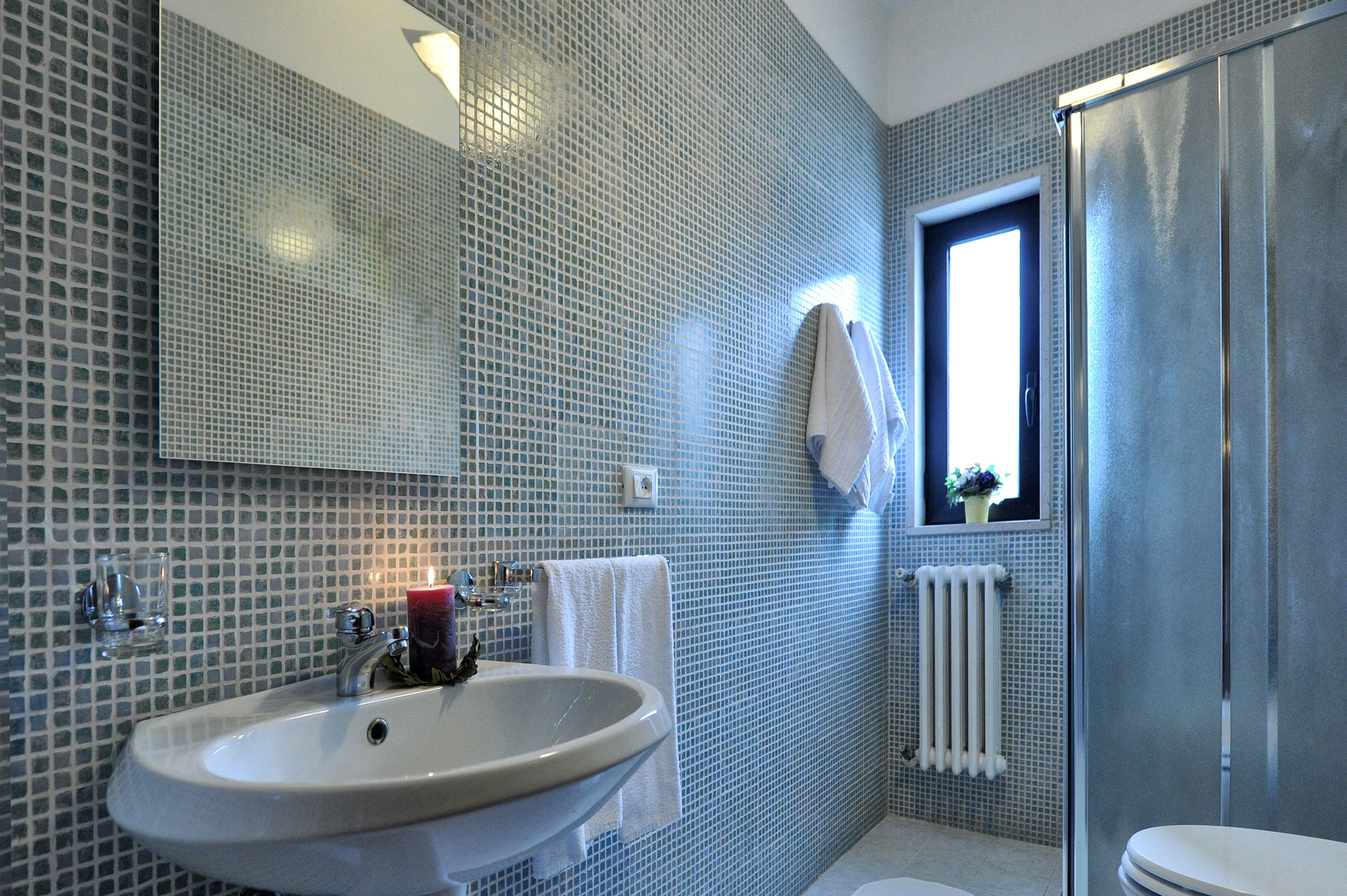 Une salle de bain avec un lavabo, un miroir et une fenêtre.