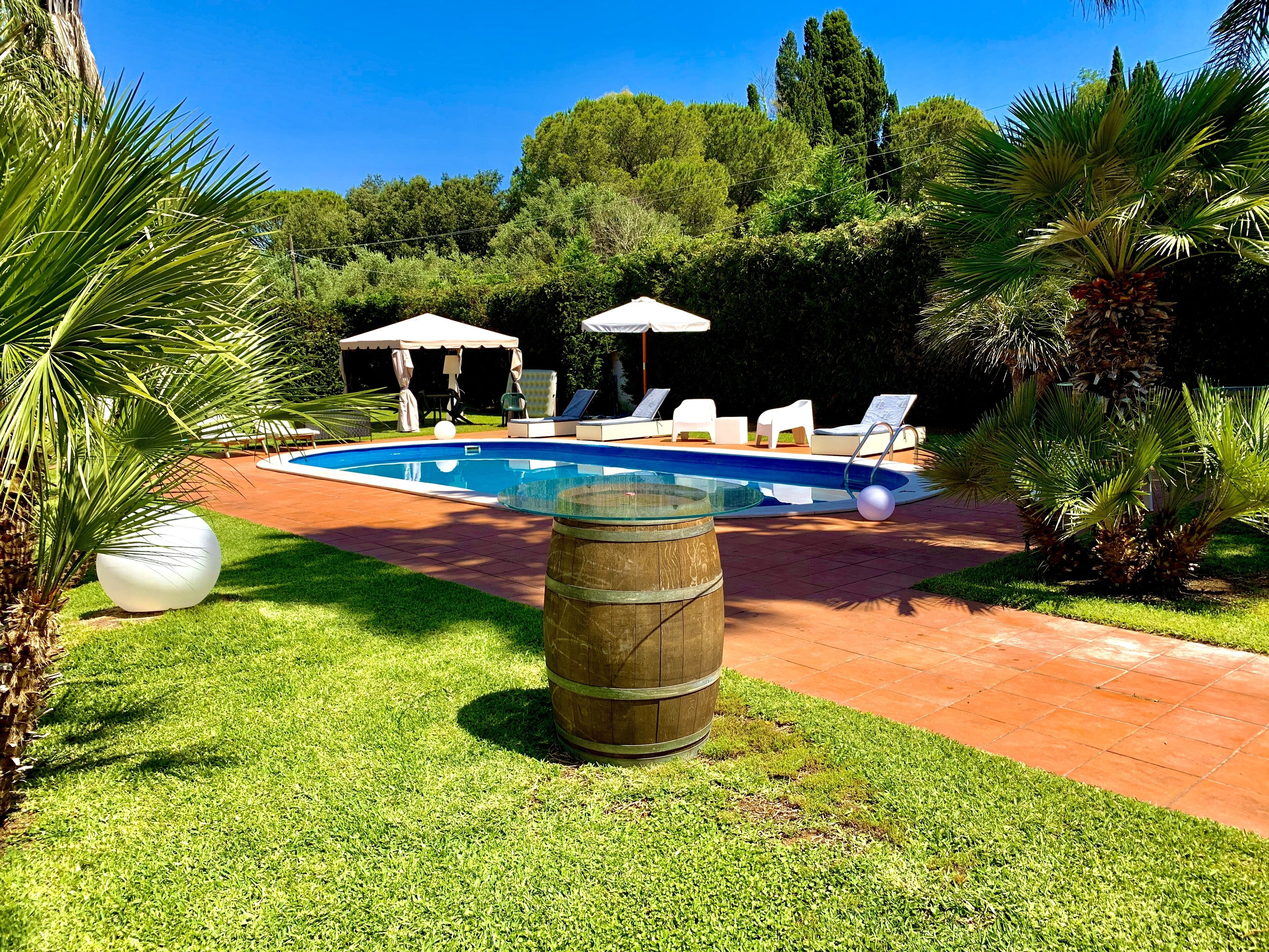 A swimming pool with lounge chairs and a covered seating area.