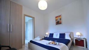 A hotel room with a bed, bedside tables, a chair, a wardrobe, and a painting on the wall. - B&B A Casa di Joy (Lecce)