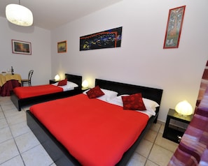 A hotel room with two beds, a dining area, and artwork on the walls. - B&B A Casa di Joy (Lecce)