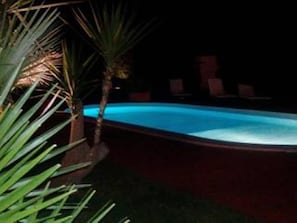 A swimming pool at night with surrounding palm trees and lounge chairs. - B&B A Casa di Joy (Lecce)