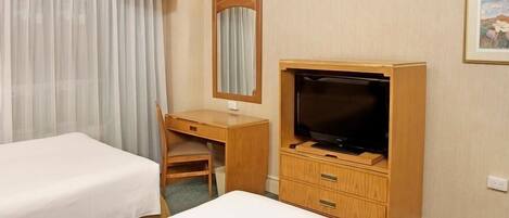 A hotel room with a bed, a desk with a chair, a television, and a mirror.